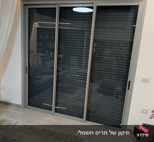 תריסים אפורים סגורים על חלון זכוכית גדול